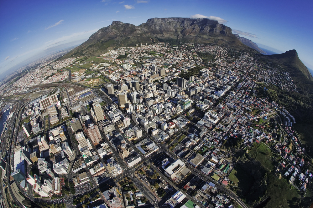 Fish-eye aerial view of the Cape Town central business district. Cape Town’s most prominent landmark, Table Mountain flanked by Devil’s Peak and Lion’s Head in the background. Western Cape Province, South Africa.