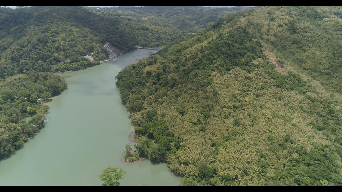 An aerial shot of the side of a mountain at the watershed facing the Ipo Dam.