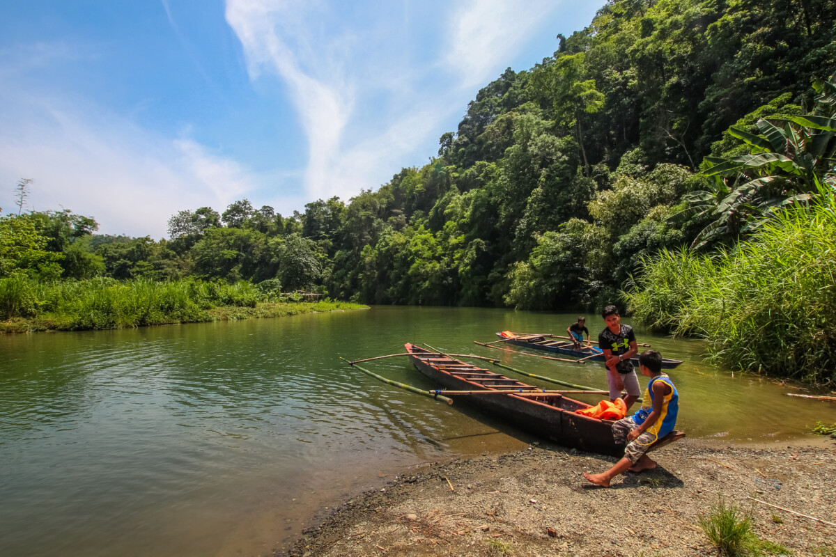 The image features two fishing boats manned by three local residents parked in the shallow waters of a river at the Ipo Watershed.